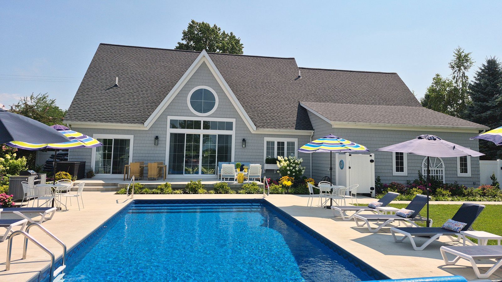 Backyard view of cottage residence, swimming pool, and sun patio